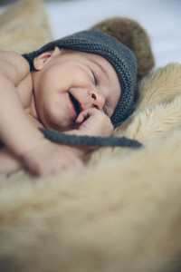 Baby girl with pompom hat sleeping and laughing