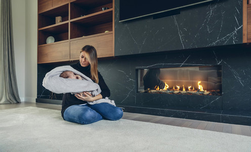 Mother hugging her baby in front of fireplace