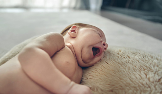 Baby yawning lying on a carpet
