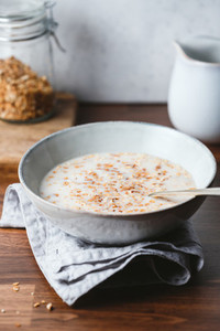 Baked granola and almond milk in a ceramic bowl on breakfast table