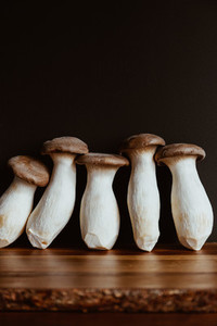 Group of raw King Oyster mushroom also known as eryngii on a wooden cutting kitchen board