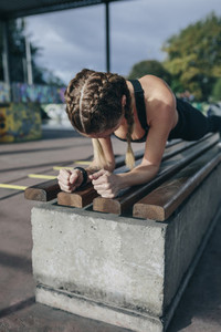 Sportswoman doing plank on a bench