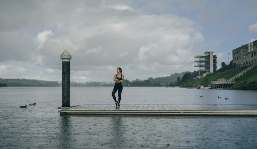 Sportswoman looking lake from pier