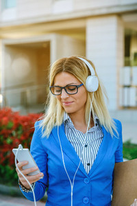 Businesswoman with headphones looking mobile
