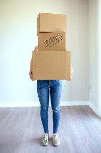 Unrecognizable woman carrying moving boxes