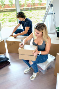 Sitting woman labeling moving boxes