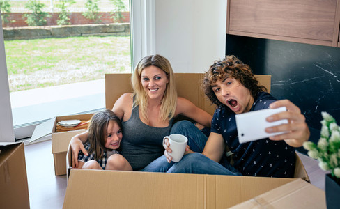 Family making selfie sitting inside moving box