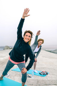 Personal trainer with senior woman with stretching side