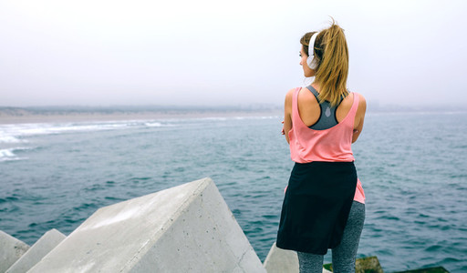 Sportswoman with headphones watching the sea