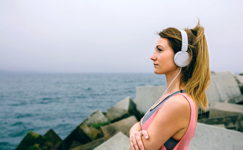 Sportswoman with headphones watching the sea