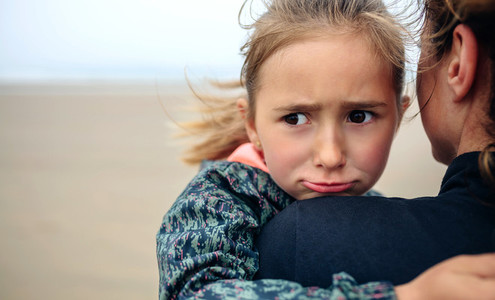 Angry girl hugging her mother on the beach