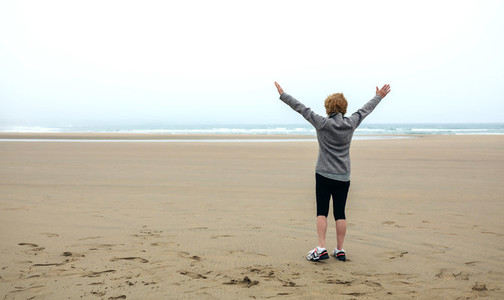 Senior woman watching the sea with hands up