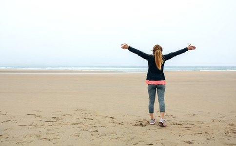 Young woman watching the sea with hands up
