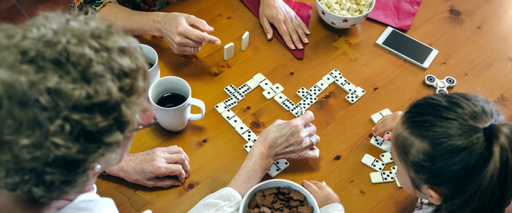 Top view of three female generations playing domino