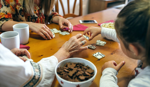 Unrecognizable three female generations playing domino