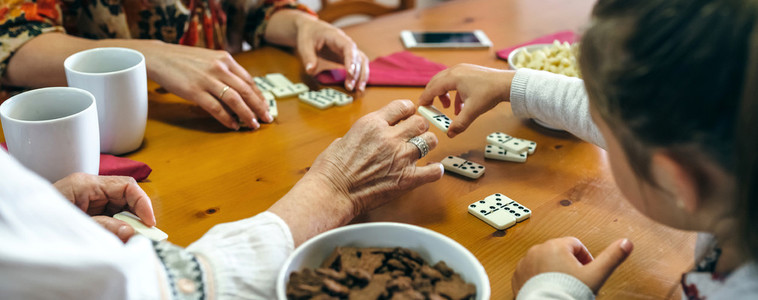 Unrecognizable three female generations playing domino