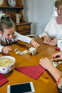 Little girl playing dominoes with mother and grandmother