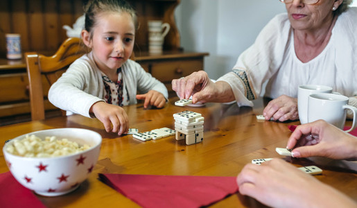 Three female generations playing with dominoes