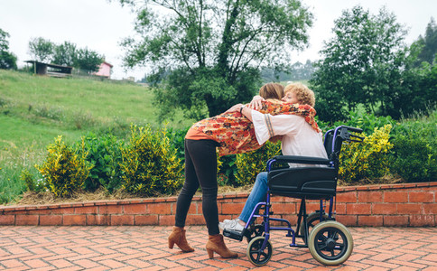 Daughter hugging her senior mother in wheelchair