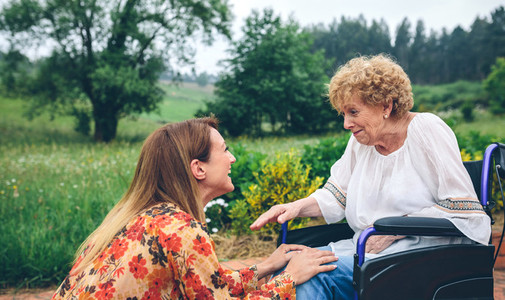 Young woman talking to elderly woman in a wheelchair