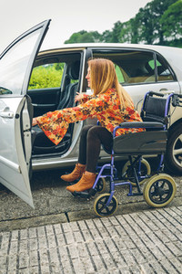 Woman in wheelchair getting on car