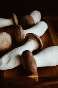 Group of raw King Oyster mushroom also known as eryngii on a wooden cutting kitchen board