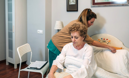 Caregiver accommodating pillow to elderly patient