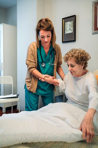 Caregiver helping elderly patient to get out of bed