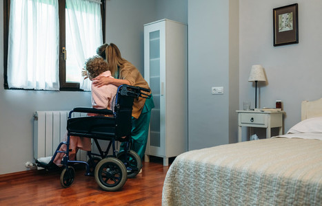 Caregiver showing the view through the window to elderly patient