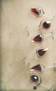 Red wine in glasses over grey concrete background  vertical composition