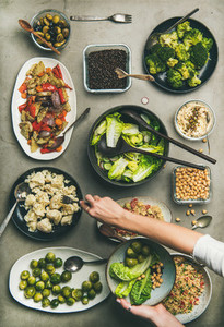 Healthy vegan dishes and woman hand taking cauliflower from plate