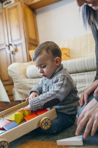 Toddler boy playing with a wooden game building