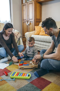 Parents playing with toddler a wooden game building