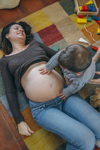 Toddler caressing belly of his pregnant mother