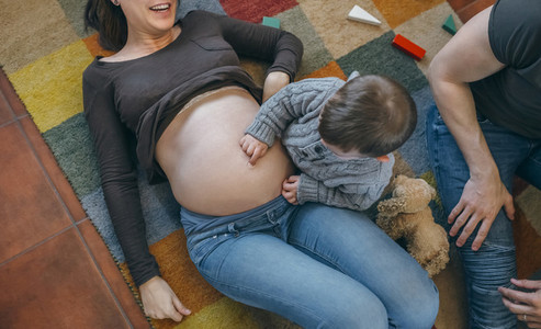 Toddler tickling the belly of his pregnant mother