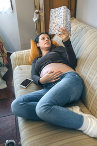 Pregnant reading a book lying on the couch