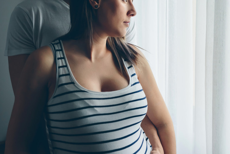 Pregnant woman embraced by her husband