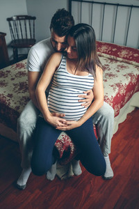 Pregnant woman embraced by her husband