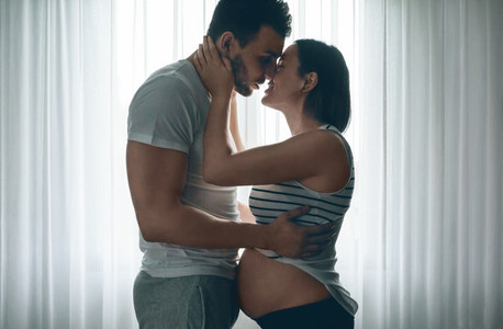 Man embracing and kissing pregnant