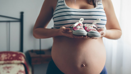 Pregnant showing baby sneakers