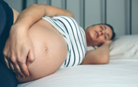 Pregnant woman sleeping in bed