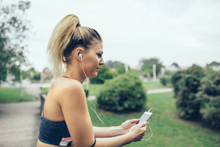Woman with earphones listening music in smartphone