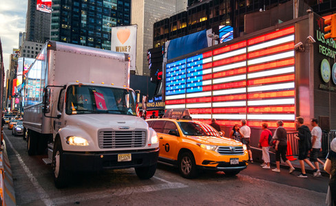 People and traffic in front of american led flag in Times Square  New York City  USA