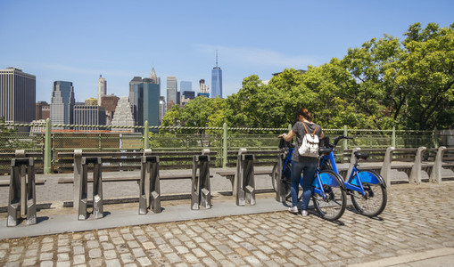 Woman taking a bike in front of Manhattan skyline in New York Ci