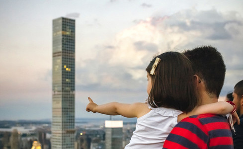 Mman holding little girl pointing skyscraper of Manhattan skylin