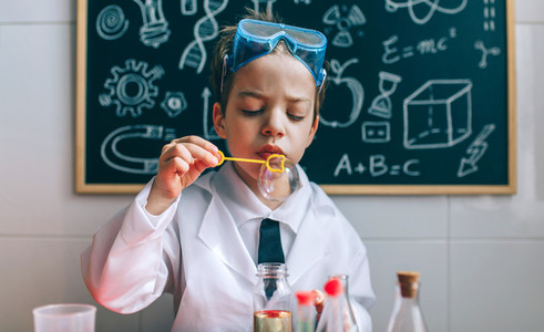 Boy playing with chemistry game blowing bubbles