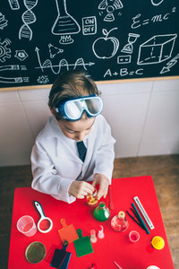 Kid playing with chemical liquids over table