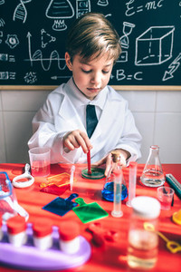 Kid playing to be chemist with colorful liquids