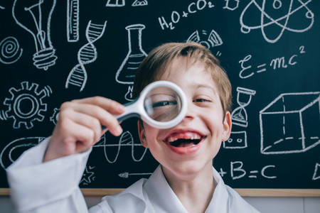 Happy kid looking at camera through magnifying glass