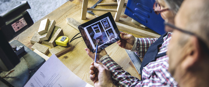 Senior couple in a carpentry looking tablet